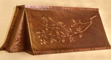 Fireplace hood with repoussé magnolia branch, in hammered copper, with solid copper straps and square bolts.