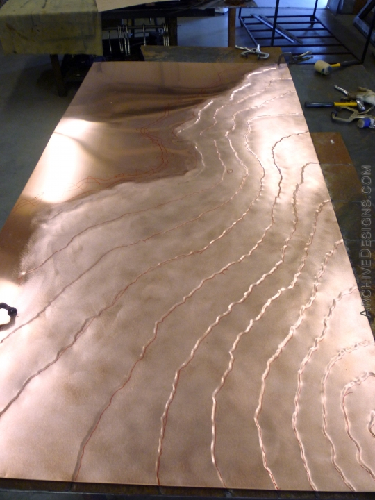 A copper panel undergoing sculpting