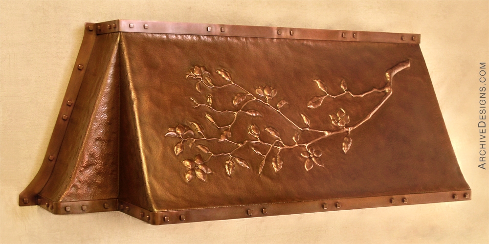 Fireplace hood with repoussé magnolia branch, in hammered copper, with solid copper straps and square bolts.